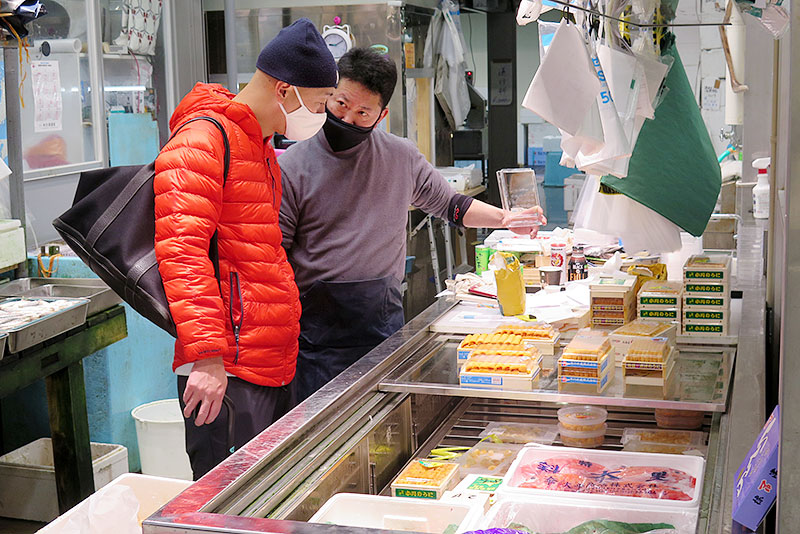 買い出しに来た高級寿司店の職人にウニを勧める伊藤社長（右）