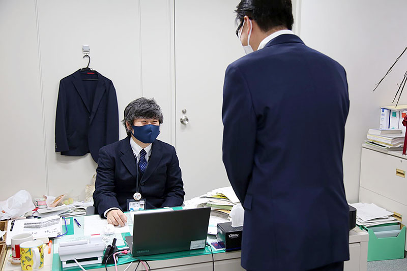 都庁の管理部長室で執務に当たる松田部長（左）。築地市場場長からの異動後も市場移転問題の最前線で活躍した